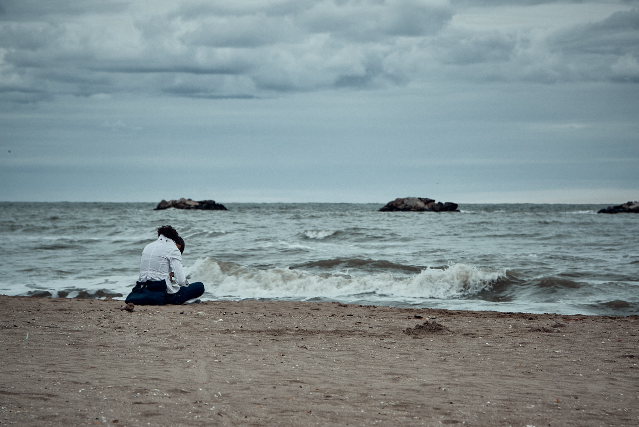 Luca Bertone - End of Season - Man sitting alone on beach facing the sea, Rimini